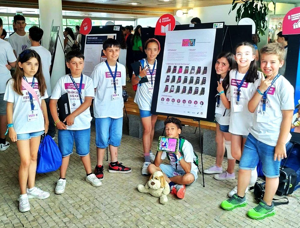 Image of 8 children posing for a camera while presenting their app Aprende Cao Diversao. This is an image related to a project inside Pedro Rodrigues (Treze413) graphic design portfolio.
