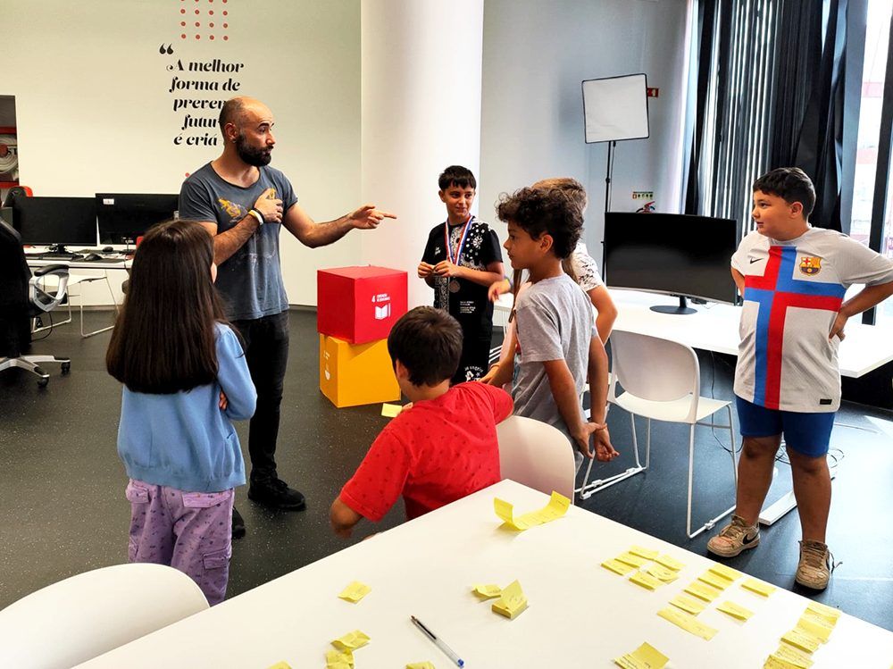 Image of an adult (myself, Pedro Rodrigues) workshopping with 6 children while standing up. This is an image related to a project inside Pedro Rodrigues (Treze413) graphic design portfolio.